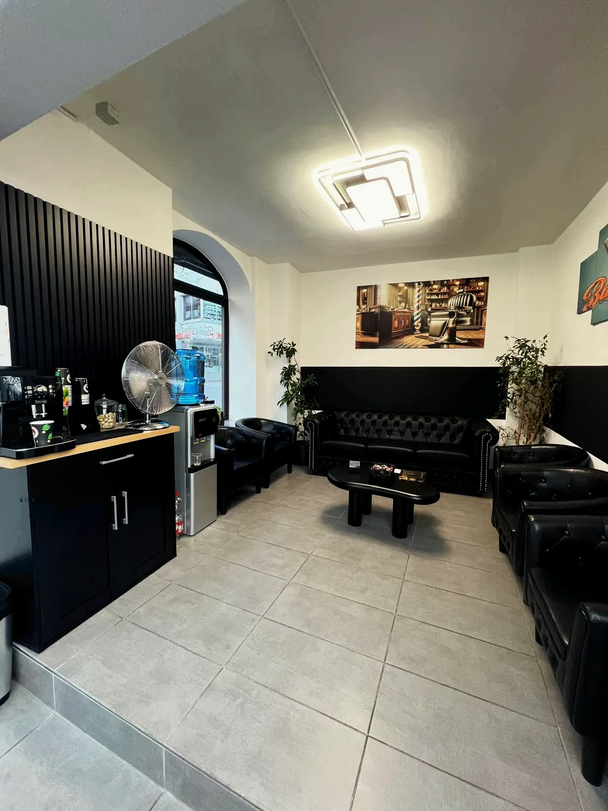 Lounge mit schwarzen Ledersofas sowie Kaffee- und Wasserstation bei Fade And Blade